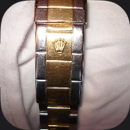 A two-tone steel and gold watch bracelet on a wrist